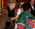 S.M. la Reina atiende a un escolar que se ha acercado hasta la mesa de cuestación de la Cruz Roja situada junto al Congreso de los Diputados