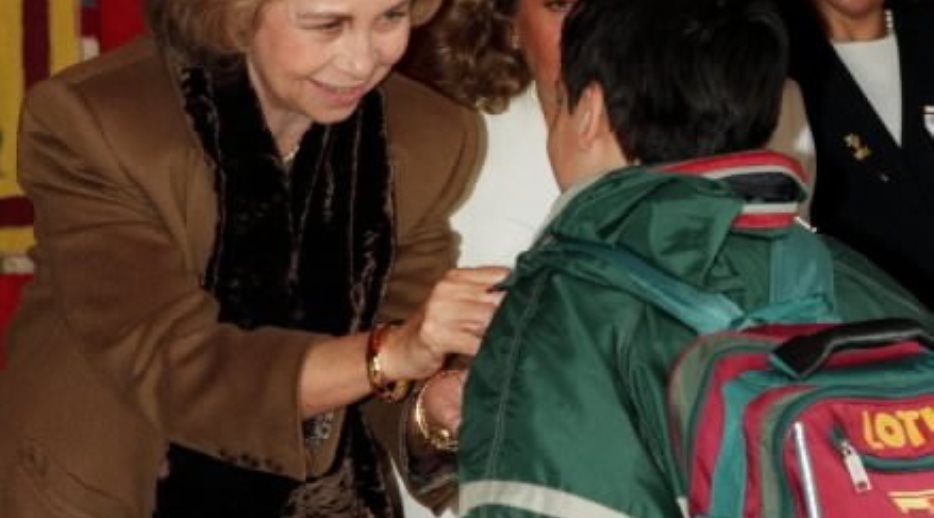 S.M. la Reina atiende a un escolar que se ha acercado hasta la mesa de cuestación de la Cruz Roja situada junto al Congreso de los Diputados