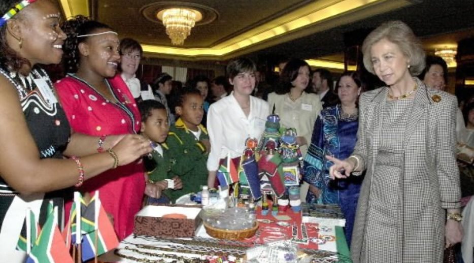 S.M. la Reina visita la mesa de Sudáfrica, durante su asistencia a la inauguración de la Kermés de la Asociación de Damas Diplomáticas