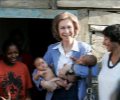 Su Majestad la Reina sostiene dos bebés durante la visita que realizó al barrio de Los Mina en Santo Domingo, a orillas del río Ozama